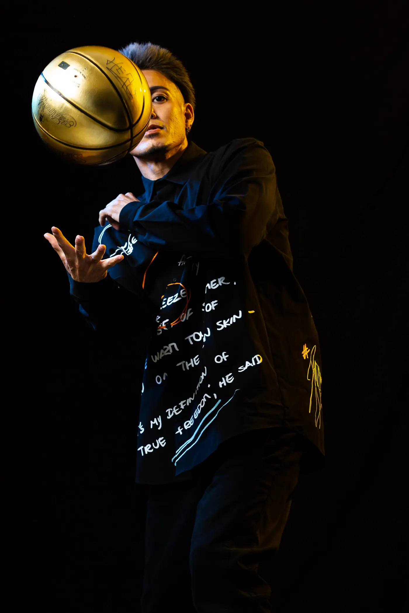 PERFORMER JJ spinning a gold ball on his fingertip